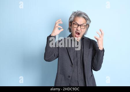 The senior Asian businessman standing on the blue background. Stock Photo