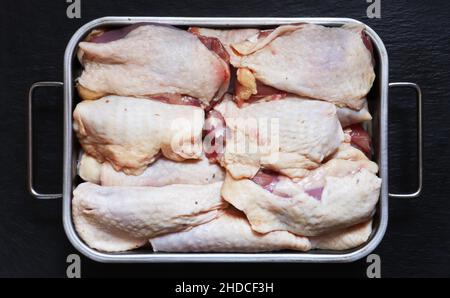 Photography of raw, boneless chicken thighs in a metal bin on slate background for food illustrations Stock Photo