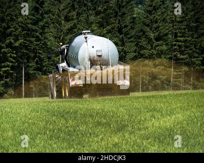 Ein Bauer fährt mit Gülle auf einem Feld zum Düngen Stock Photo