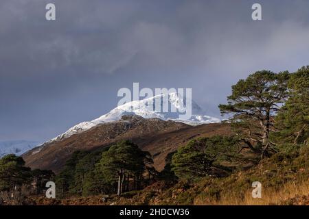 A brief period of light illuminates the snow capped mountain,  Sgùrr na Lapaich. Glen Affric, Highland, Scotland Stock Photo