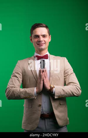 Portrait of male announcer holding microphone, isolated on green, white background Stock Photo