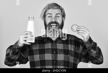 bakery goods concept. his favorite food. enjoying freshly baked pastries. happy farmer eat dessert. bearded man drink useful milk with pastry. cookie Stock Photo