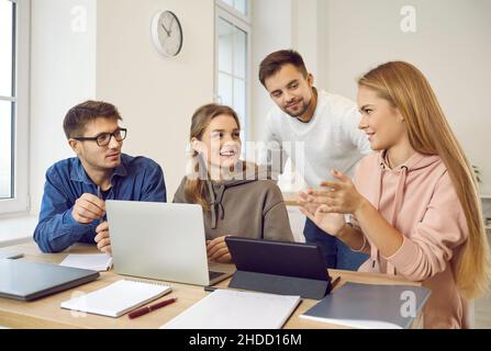 Group of happy university students discussing something while working on project together Stock Photo