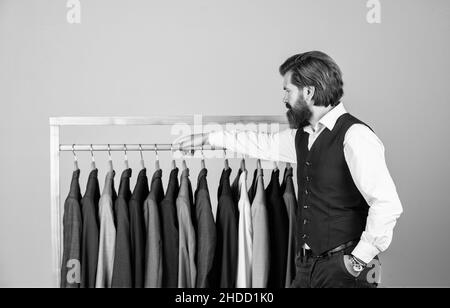 Man picking suit from personal wardrobe, tailored blazer concept Stock Photo