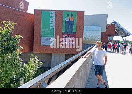 Weisman Art Museum at the University of Minnesota student leaning on bannister designed by Architect Frank Gehry. Minneapolis Minnesota MN USA Stock Photo