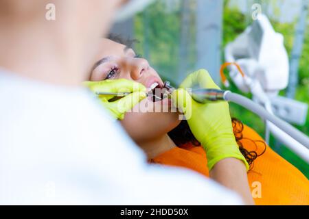 Beautiful mixed-race teenage girl  having dental checkup. Young woman undergoing teeth whitening procedure. Stock Photo