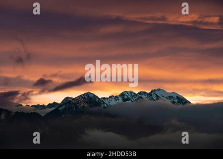 dark afterglow at sunset over the fog-shrouded austrian alps mountains in autumn Stock Photo