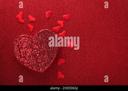 Red openwork gift boxes in shape of heart with small red decorative hearts on red background. Top view with copy space. Valentines day or Wedding roma Stock Photo