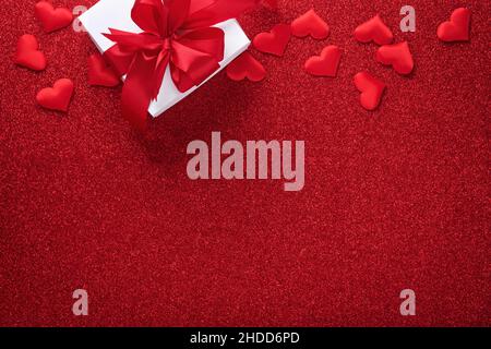 White gift boxes with red ribbon and small red decorative hearts on red background. Top view with copy space. Valentines day or Wedding romantic conce Stock Photo