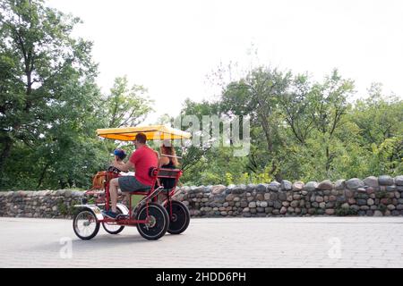 Family peddling a four wheel cycle at Minnehaha Falls Park. Minneapolis Minnesota MN USA Stock Photo