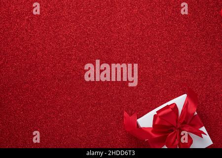 White gift boxes with red ribbon and small red decorative hearts on red background. Top view with copy space. Valentines day or Wedding romantic conce Stock Photo