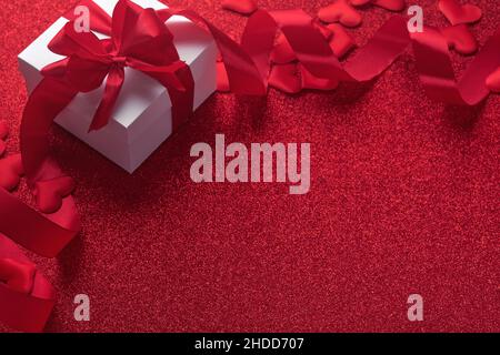 White gift boxes with red ribbon and small red decorative hearts on red background. Top view with copy space. Valentines day or Wedding romantic conce Stock Photo
