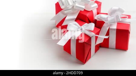 Red gift boxes with white bow on a white table. Stock Photo