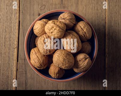 Walnuts in a ceramic bowl on a dark wooden background Stock Photo
