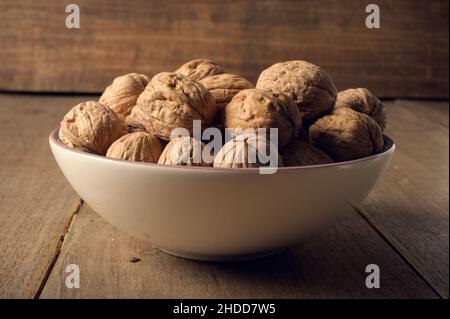 Walnuts in a ceramic bowl on a dark wooden background Stock Photo