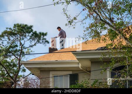 NEW ORLEANS, LA, USA - DECEMBER 31, 2021: Worker setting chimney pot on chimney during roof renovation Stock Photo