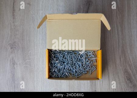 Top view of tapping screws in a corrugated cardboard box on a wooden background Stock Photo