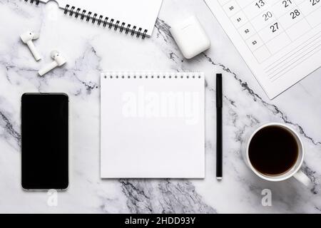 Cup of coffee, phone, headphones, calendar and notebook paper on the marble table. Flat design, planning concept, goal setting, monochrome style. Blac Stock Photo