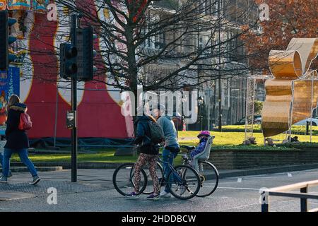 A family crossing traffic light with their bikes and child Stock Photo