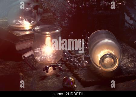 Magic festive lights with sparkles and orange glow in vintage glass jars. Lights and old books. Fir twigs and heather flowers. Romantic evening Stock Photo