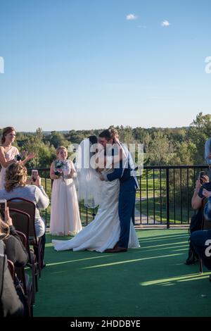 Minnesota, USA.   Bride and groom with the traditional kiss after getting married in front of their guests. Stock Photo