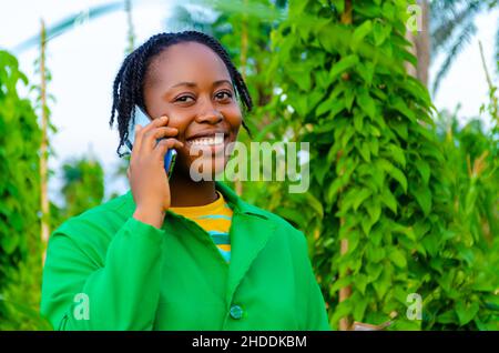 pretty african woman in the farm making calls in the farm while holding money on her other hand Stock Photo