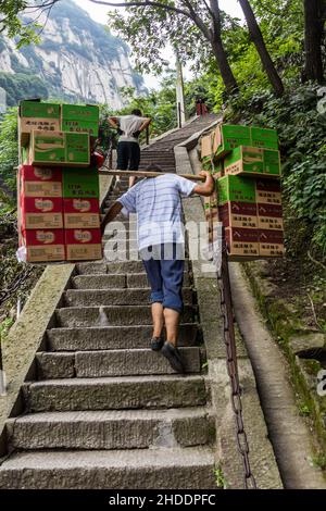 HUA SHAN, CHINA - AUGUST 4, 2018: Porter at the stairs leading to the peaks of Hua Shan mountain, China Stock Photo