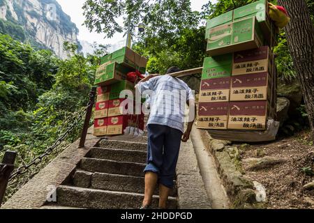 HUA SHAN, CHINA - AUGUST 4, 2018: Porter at the stairs leading to the peaks of Hua Shan mountain, China Stock Photo