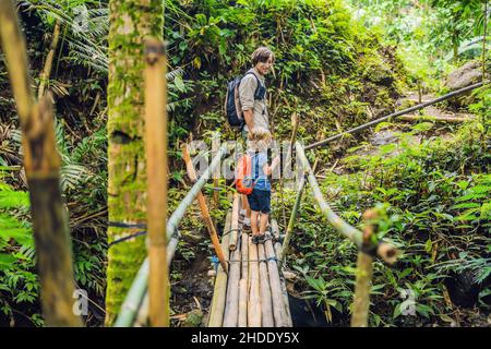Father and son travelers on the suspension bridge in Bali. Traveling with children concept. Stock Photo