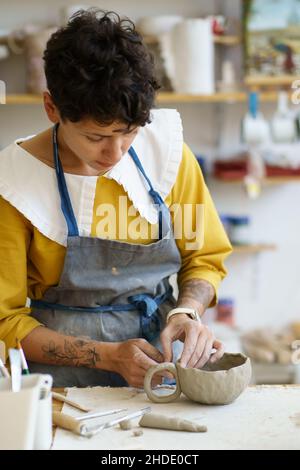 Young woman qualified ceramics teacher showing handmade pottery making process during masterclass Stock Photo