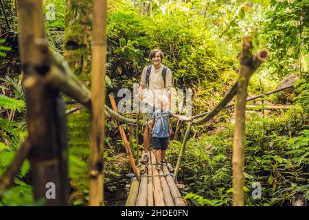 Father and son travelers on the suspension bridge in Bali. Traveling with children concept. Stock Photo