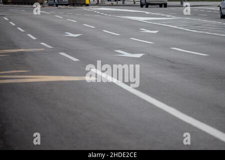 Picture of road lanes on a city streey with various directional arrows painted in white as markings. Stock Photo