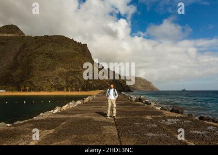 A man on the ocean on the rocks. Stone Beach in Tenerife. A man is relaxing on the beach, pondering, calm, muse Stock Photo