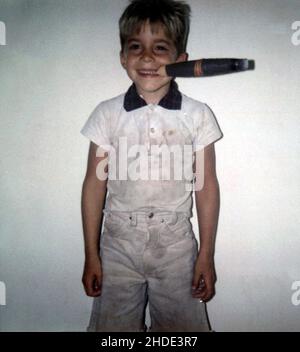 A little boy in dirty clothes posing with a fake cigar in his mouth, circa 1970 Stock Photo