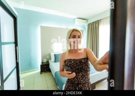 Side view pleasant young woman using smart home system or activating modern alarm system before leaving apartment. Happy lady turning off easy Stock Photo