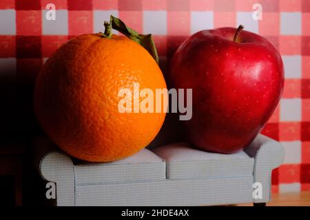 Comparing apples to oranges idiom concept with fruit sitting on sofa Stock Photo