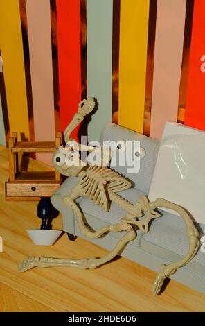 Concept for how overwhelming creativity can be, shown as a crazy skeleton at home on the couch Stock Photo