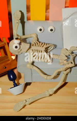 Concept for how overwhelming creativity can be, shown as a crazy skeleton at home on the couch Stock Photo