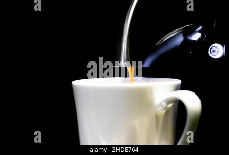 Coffee maker espresso machine nose above a coffee cup. with cofee dripping pouring into it. With copy space. Concept- routine, coffee, coffee-dependanc Stock Photo