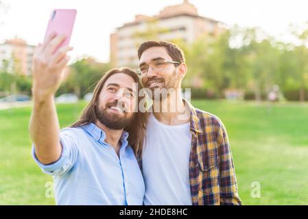 A happy gay couple taking a selfie in the park Stock Photo