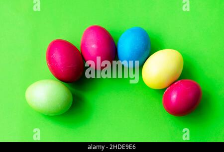 Easter themes. Multi-colored colored eggs on a bright green background. Postcard. Greetings. Copy space for text. Stock Photo