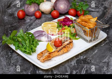 Grilled salmon with salad and french fries on a white plate Stock Photo