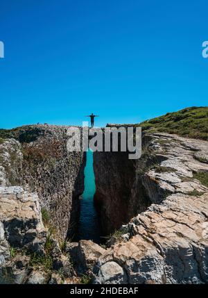 Back view of a man standing on the edge of a cliff on a sunny day. Kilimli Cove in Agva istanbul. Stock Photo