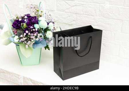 black empty paper bags and bouquets. Blank wall Stock Photo