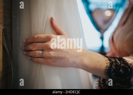 Closeup shot of the bride's hand holding her wedding gown Stock Photo