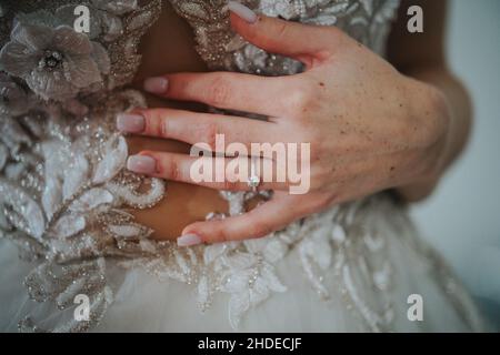 Closeup shot of the bride's hand holding her wedding gown Stock Photo