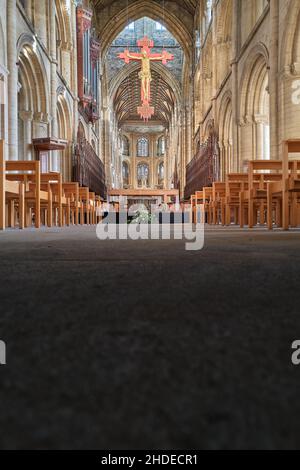 A modern (1975) crucifix of Jesus Christ hangs above the nave in the medieval cathedral at Peterborough, England. Stock Photo