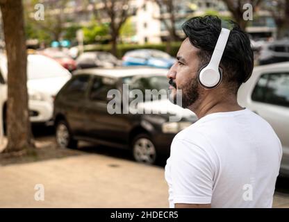 medium shot of latin man with beard walking in buenos aires city with headphones Stock Photo