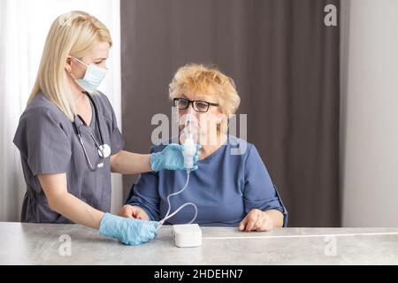 Young Female Doctor Holding Oxygen Mask Over Senior woman Patient's Face. Stock Photo