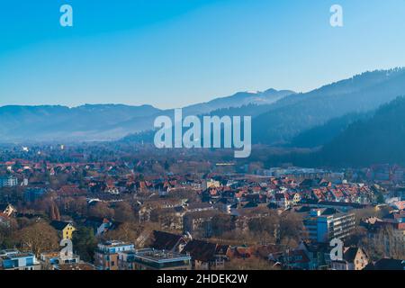 Germany, Freiburg im Breisgau cityscape houses in valley between black forest mountains schauinsland covered by snow on cold winter day Stock Photo